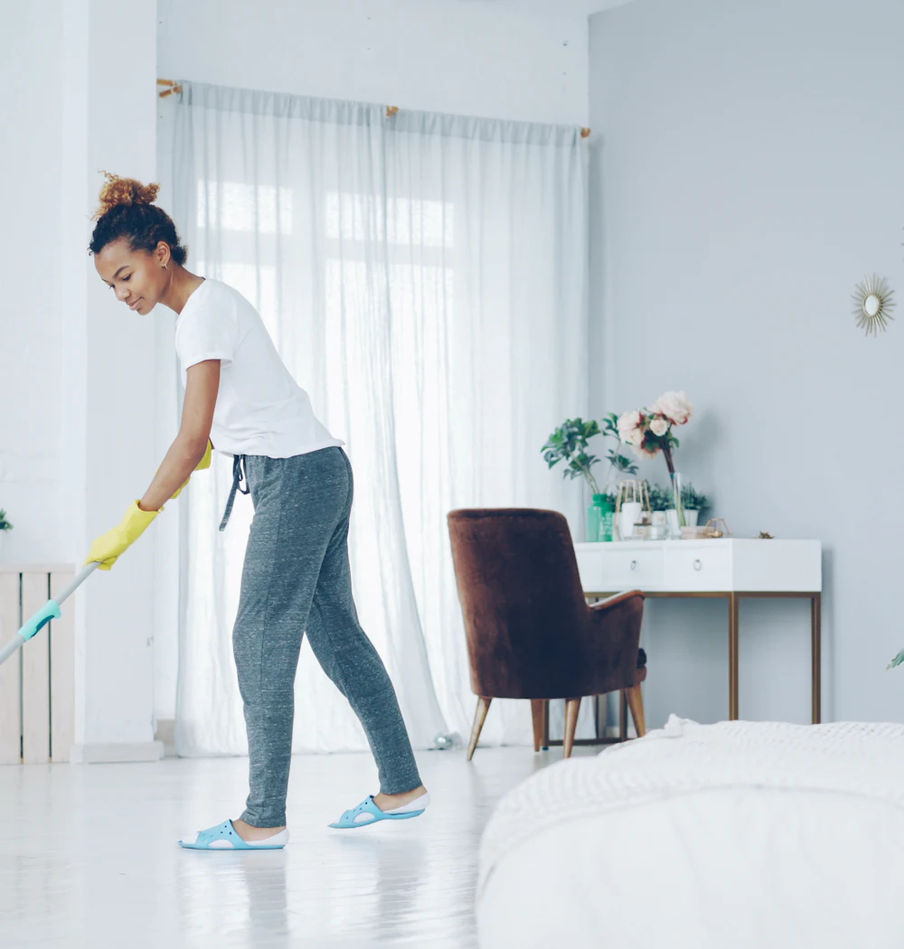 A cleaner mopping the floor of a bright living room
